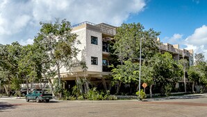 A multi-story building with a stone facade, balconies, and a paved area in front. - Depto en Cancun 506 by Sinbad (Cancun)