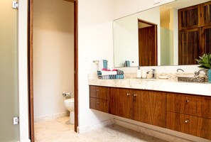 A bathroom with a wooden vanity, a large mirror, and a toilet. - Depto en Cancun 506 by Sinbad (Cancun)