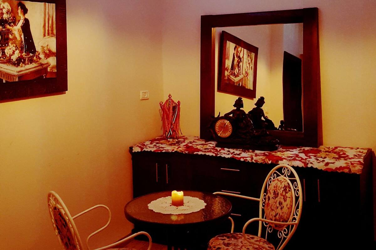 Uma sala de jantar com mesa, cadeiras, lustre e obras de arte nas paredes.