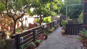 Un chemin pavé de briques bordé de plantes en pot et agrémenté d’un hamac.