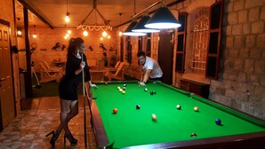 Une table de billard dans une pièce aux murs en pierre et aux meubles en bois.