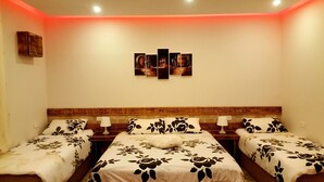 Une chambre d’hôtel avec deux lits simples, une tête de lit en bois, une œuvre d’art accrochée au mur et un mur d’accent de couleur rouge.