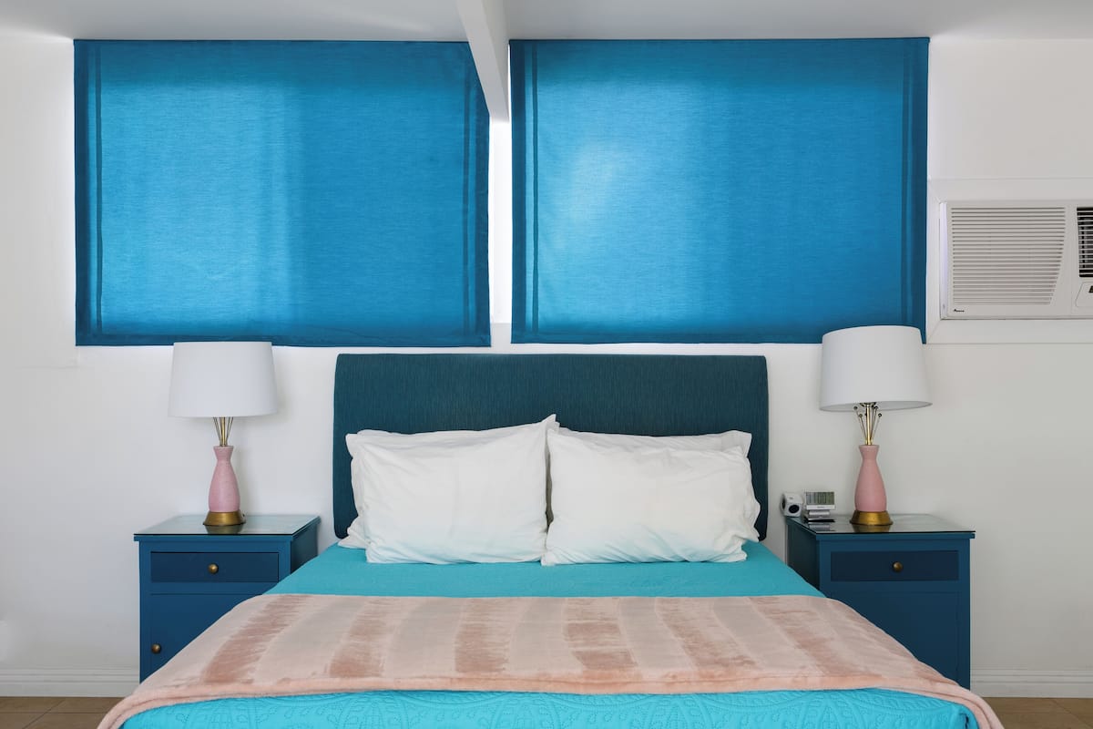 Ein Schlafzimmer mit einem großen Bett, zwei Nachttischen und einer Wand-Klimaanlage.
