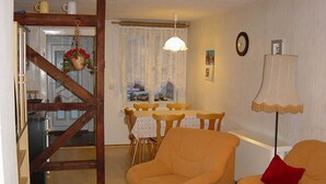 Una sala de estar acogedora con un sofá, una mesa de comedor con sillas y una escalera que lleva a otra habitación.