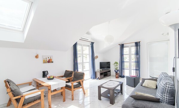 A bright living room with a dining area, a sofa, and a TV.