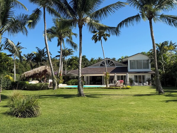 A modern house with a pool, surrounded by palm trees and a well-maintained lawn.