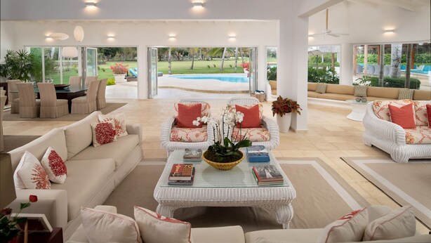 A spacious living area with a large window overlooking a swimming pool, furnished with white sofas and a central coffee table. - Punta Aguila Spectacular 4 Bdr / 6 Bath Free Golf Cart  Chef and Waiter Included (La Romana)