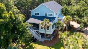 A light blue two-story house with a covered porch and a staircase leading to the upper level. - Ample outdoor living spaces, Short walk to beach, Get a little "Sand In Your Shoes' (Folly Beach)