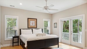 A bedroom with a bed, a ceiling fan, and a view of the outdoors through a sliding door. - Ample outdoor living spaces, Short walk to beach, Get a little "Sand In Your Shoes' (Folly Beach)