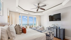 A bedroom with a bed, a ceiling fan, a TV, a dresser, and a view of the ocean. - 6 BR + Bonus Room, Luxury Oceanfront, Pets ok, Elevator, 2 Living Rooms - The Loggerhead (Folly Beach)