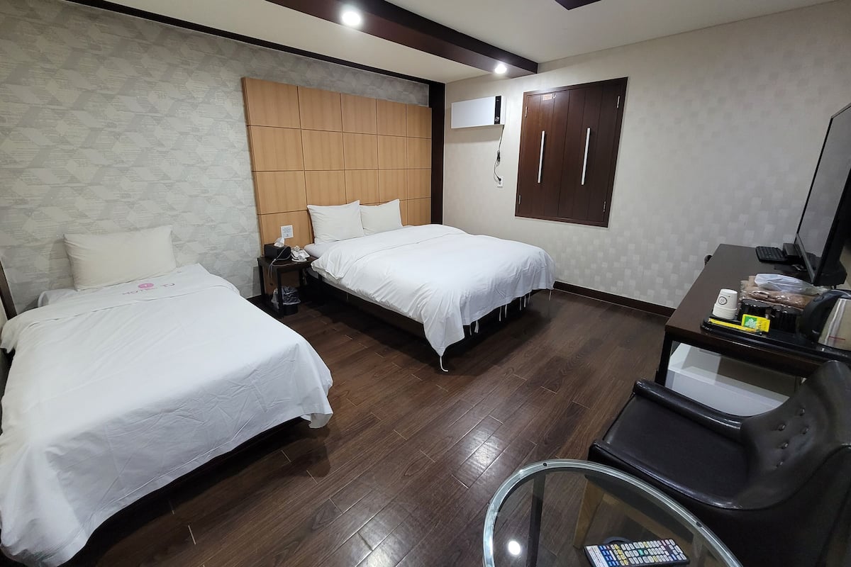 A hotel room with two beds, a desk with a computer, and a chair.