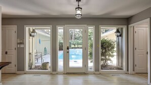 Ein großzügiger Eingangsbereich mit einer großen Glasdoor, die zu einem Garten mit Pool führt.