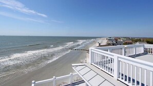Une propriété située en bord de mer, dotée d’un balcon blanc donnant sur l’océan.