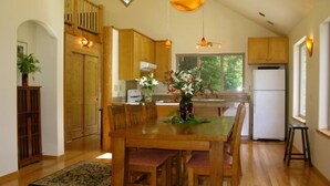 A spacious kitchen with wooden cabinets, a dining table with chairs, and a refrigerator. - Beautiful, Warm & Welcoming-Redwoods, River, Beaches includes Hot tub (Arcata)