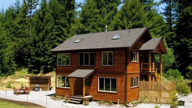 A two-story wooden cabin with a covered porch, a deck, and a small staircase leading to an upper level. - Beautiful, Warm & Welcoming-Redwoods, River, Beaches includes Hot tub (Arcata)
