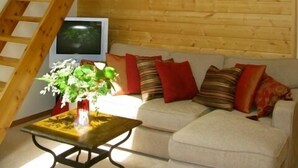 A loft-style room with a wooden staircase, a flat-screen TV, a sofa with cushions, and a small table with a plant. - Beautiful, Warm & Welcoming-Redwoods, River, Beaches includes Hot tub (Arcata)