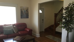 A living room with a red sofa, a coffee table, and a chessboard. There is a painting on the wall and a plant in the corner. - Victorian! Professionally Cleaned, Self Check In - Sleeps 10 (Kenosha)