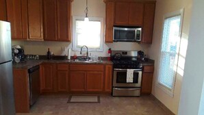 A kitchen with wooden cabinets, a stainless steel refrigerator, a microwave, a stove, and a sink. - Victorian! Professionally Cleaned, Self Check In - Sleeps 10 (Kenosha)