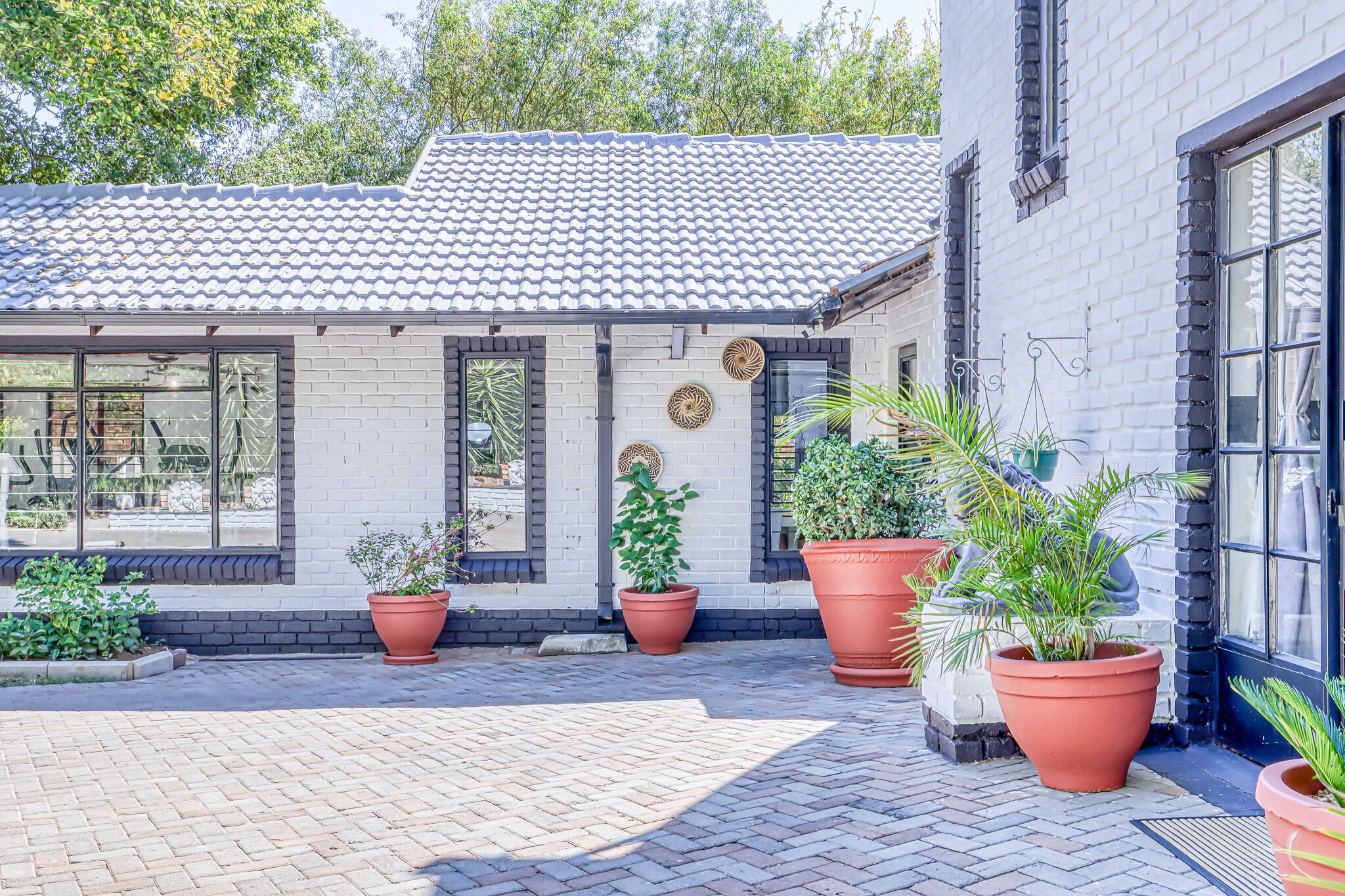 A building with a tiled roof, large windows, and potted plants.