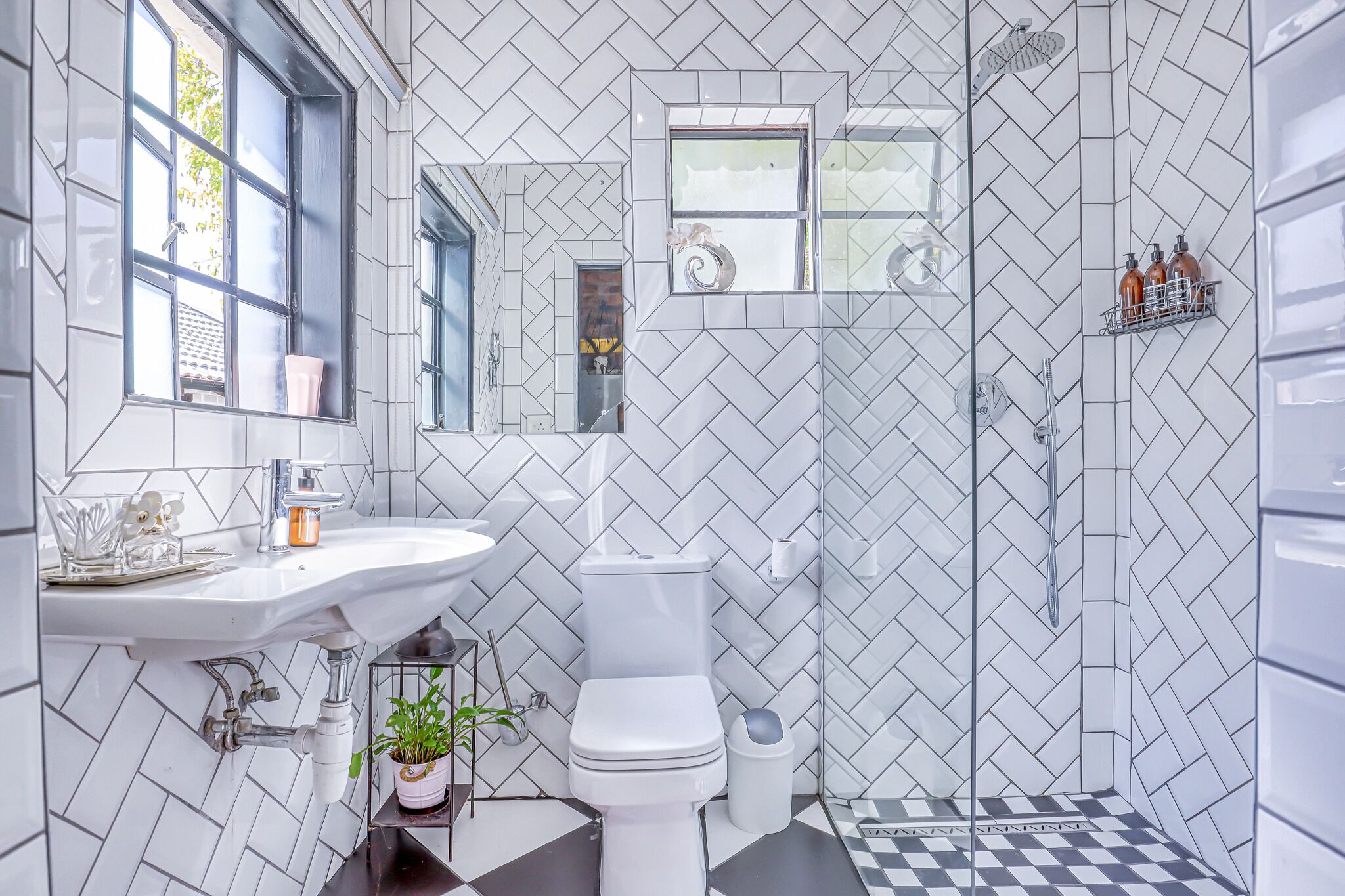Un bany modern amb un mosaic d'aparelleria de veta de peix, un rentapeus blanc, un vàter i una zona de dutxa.