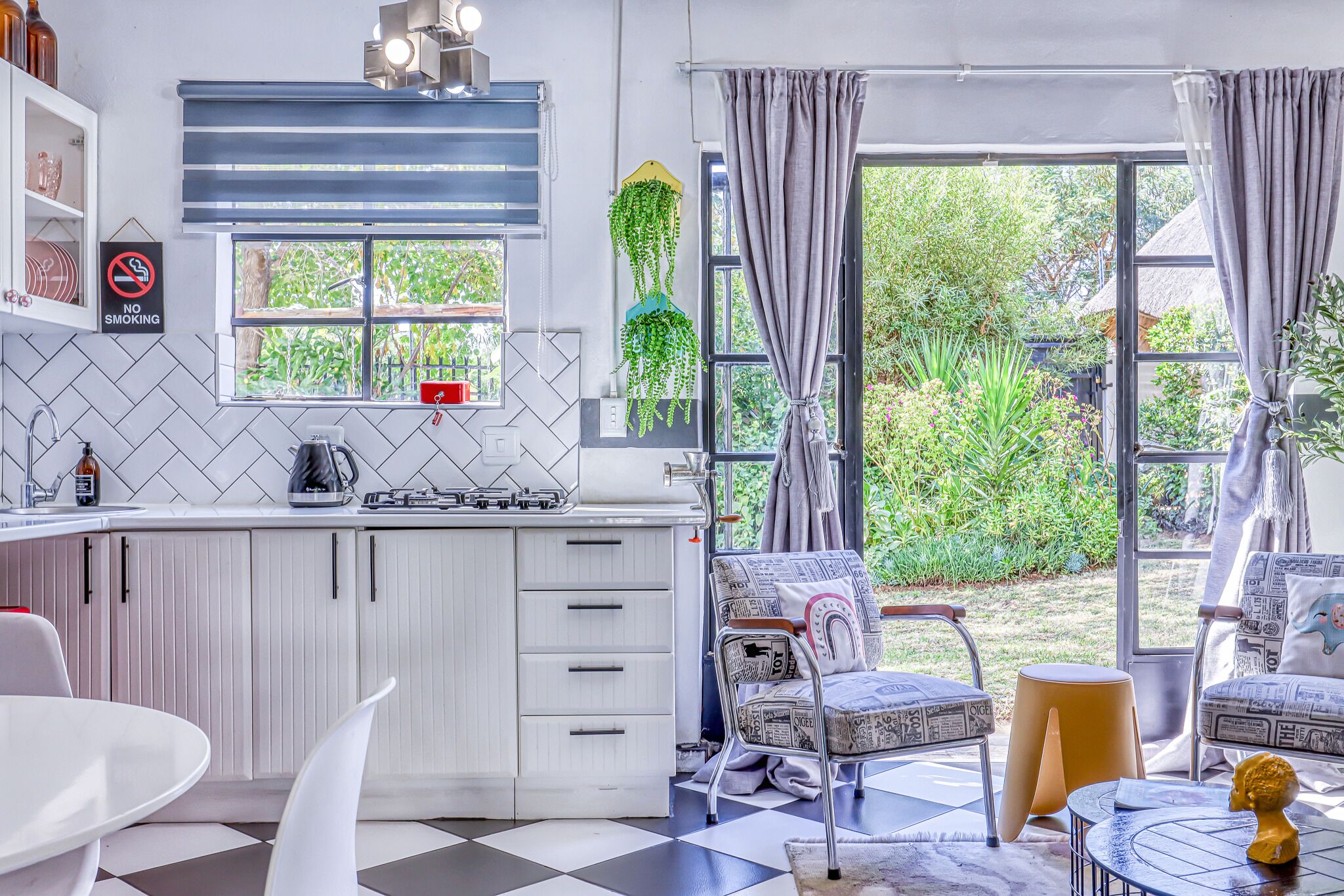 A modern kitchen with white cabinets, a gas stove, and a window overlooking a garden.