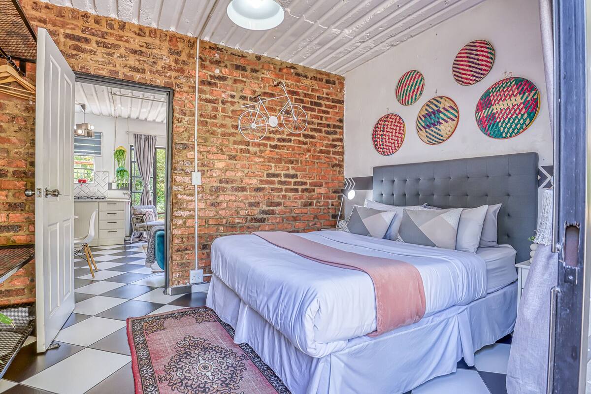 A bedroom with a large bed, a brick wall, and a checkered floor.