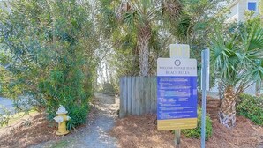 Ein hölzernes Tor mit einem Schild, das Besucher in Folly Beach willkommen heißt und die Regeln für den Strand aufführt.
