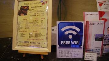 Eine Speisekarte mit Speisen und Getränken, ein Schild für kostenloses WLAN und ein Schild zur Vermietung von LAN-Karten.