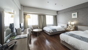 Une chambre d’hôtel avec deux lits, un bureau avec une chaise, une petite table ronde et un miroir.