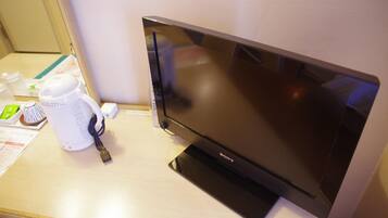 A Sony TV on a wooden desk with a white mug and a power strip.