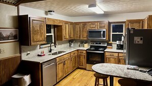A modern kitchen with wooden cabinets, a stainless steel refrigerator, a microwave, and a gas stove. - Panoramic Country Views ~ Wildlife ~ Butterflies & Birds ~ Star-gazing ~ Hiking (Leakey)