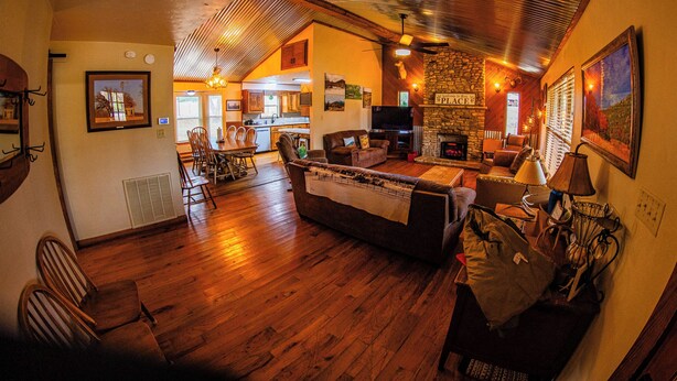 A cozy living room with a fireplace, wooden floors, and a dining area with chairs and a table. - Panoramic Country Views ~ Wildlife ~ Butterflies & Birds ~ Star-gazing ~ Hiking (Leakey)