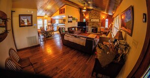 A cozy living room with a fireplace, wooden floors, and a dining area with chairs and a table. - Panoramic Country Views ~ Wildlife ~ Butterflies & Birds ~ Star-gazing ~ Hiking (Leakey)