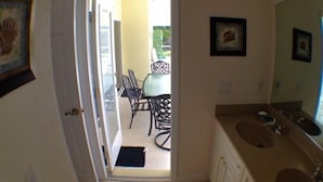 A narrow hallway leading to a dining area with a table and chairs, a bathroom with a sink and mirror, and a door leading outside. - 3 Bedroom Home with Heated Private Pool Close to Golf & Beach (Rotonda lakes)
