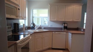 A kitchen with white cabinets, a dishwasher, a stove, and a window providing natural light. - 3 Bedroom Home with Heated Private Pool Close to Golf & Beach (Rotonda lakes)