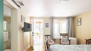 A bedroom with a bed, a chair, a desk, and a television.