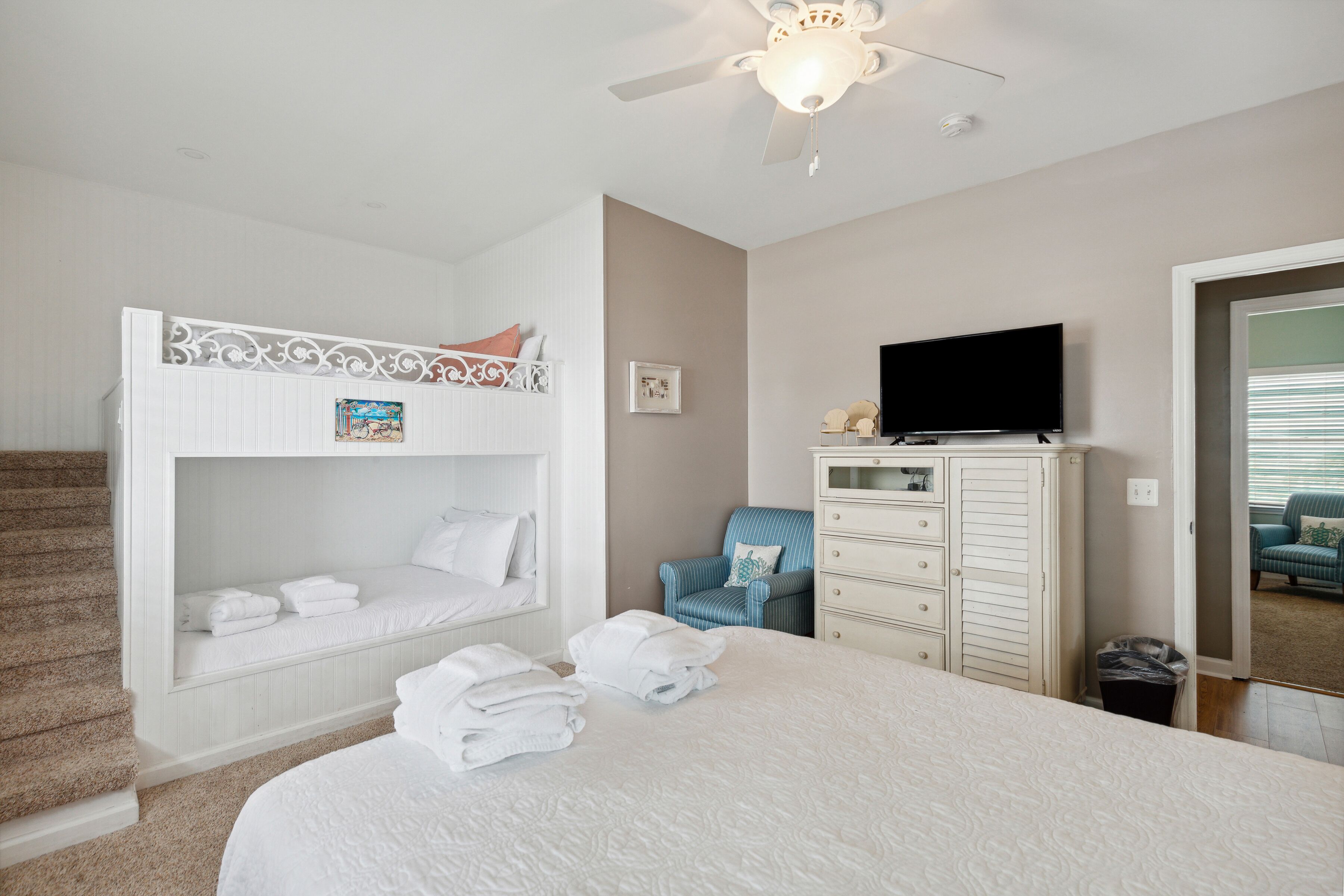 A bedroom with a bunk bed, a flat-screen TV, a dresser, and a chair.