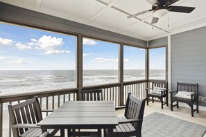 Enjoy ocean views from this covered outdoor space with a table, chairs, and ceiling fan.