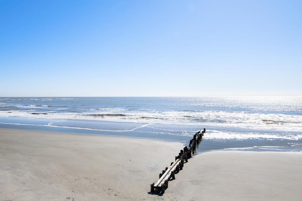Une plage avec un brise-lames en bois qui s’avance dans la mer, servant de digue.
