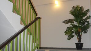 A staircase with green railings and grey tiles, a potted plant, and a wall-mounted light fixture. - Hotel Wawasan (Simpang Renggam)