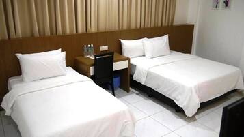 A hotel room with two single beds, a wooden headboard, a small desk with a chair, and a blue trash bin.