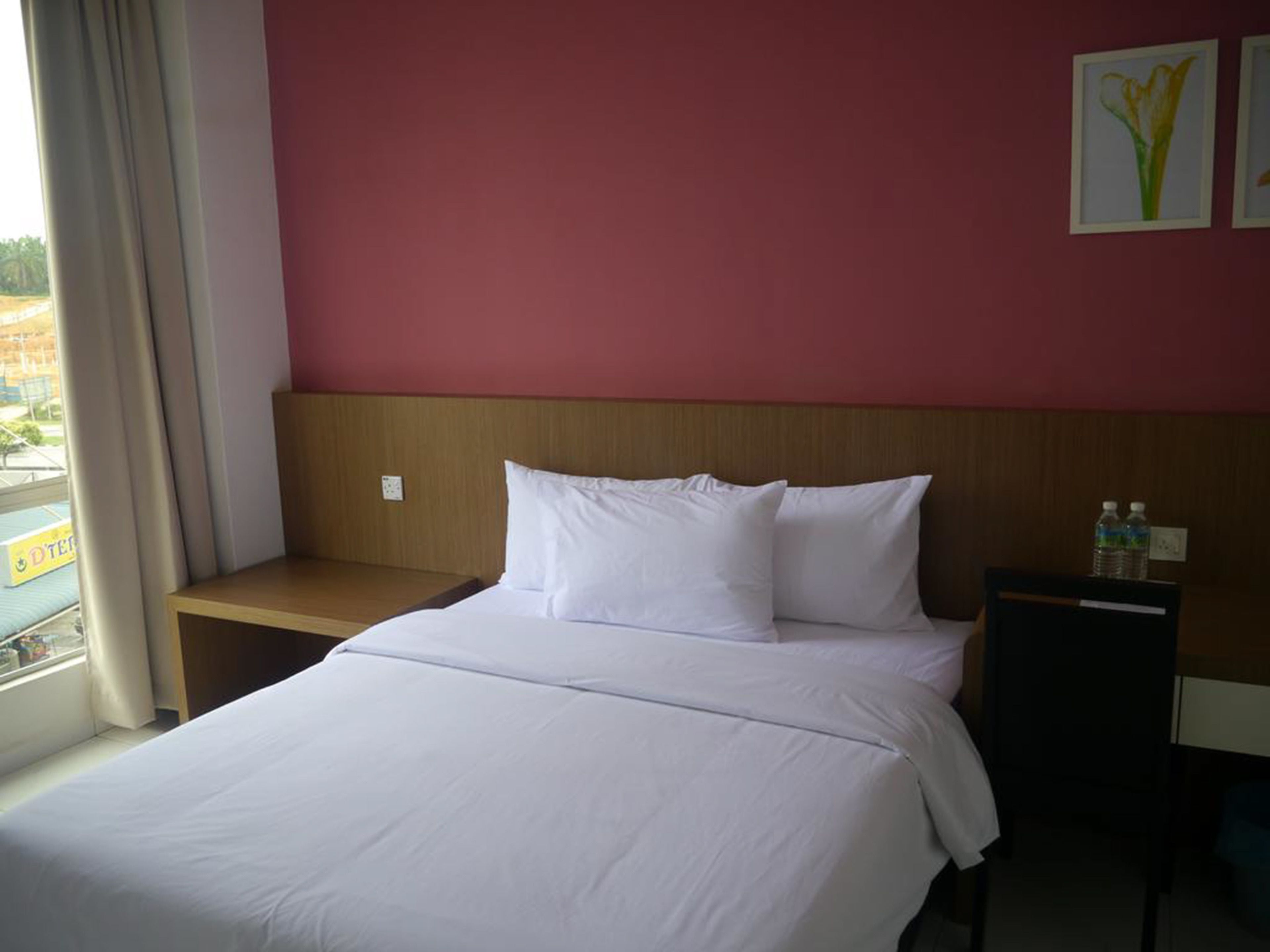 Ein Hotelzimmer mit einem Bett, einem Nachttisch, einem Holz-Kopfteil und einem Fenster mit Vorhängen.