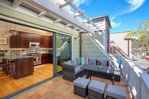 A spacious patio with a dining area, a kitchen with modern appliances, and a sliding glass door leading to an indoor space. - Beachy Keen:  2 master ensuites, steps from beach, rooftop BBQ (Avila Beach)