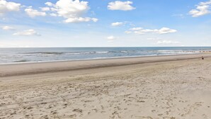 A wide sandy beach with footprints and a clear sky. - Ocean, Marsh, & River Views! Dock For Fishing & Sunsets (Folly Beach)