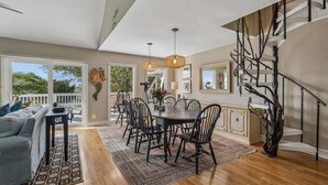 A dining area with a round table, chairs, and hanging lights. - Ocean, Marsh, & River Views! Dock For Fishing & Sunsets (Folly Beach)