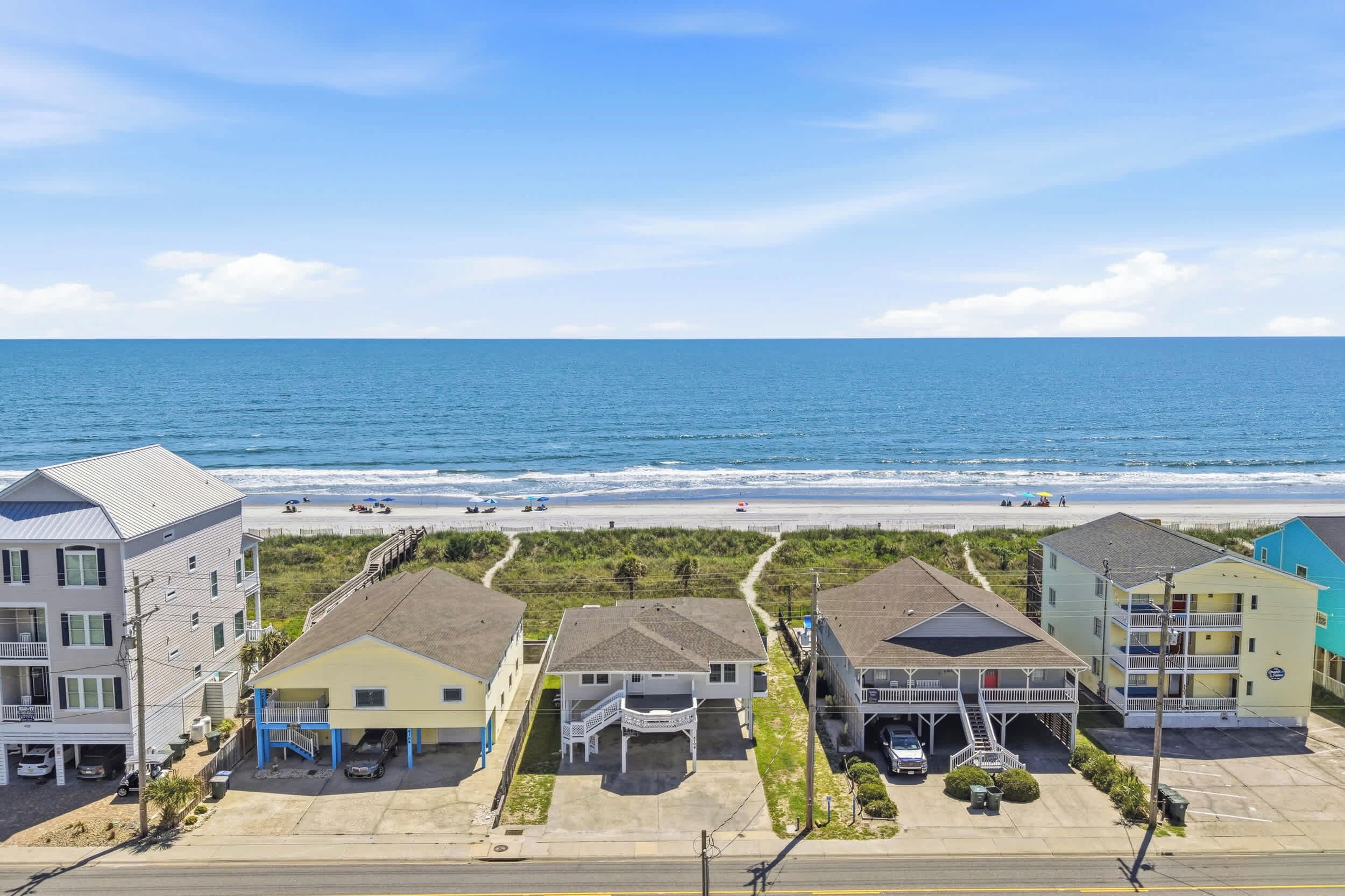 A beachfront property with a parking lot, a boardwalk, and a view of the ocean.