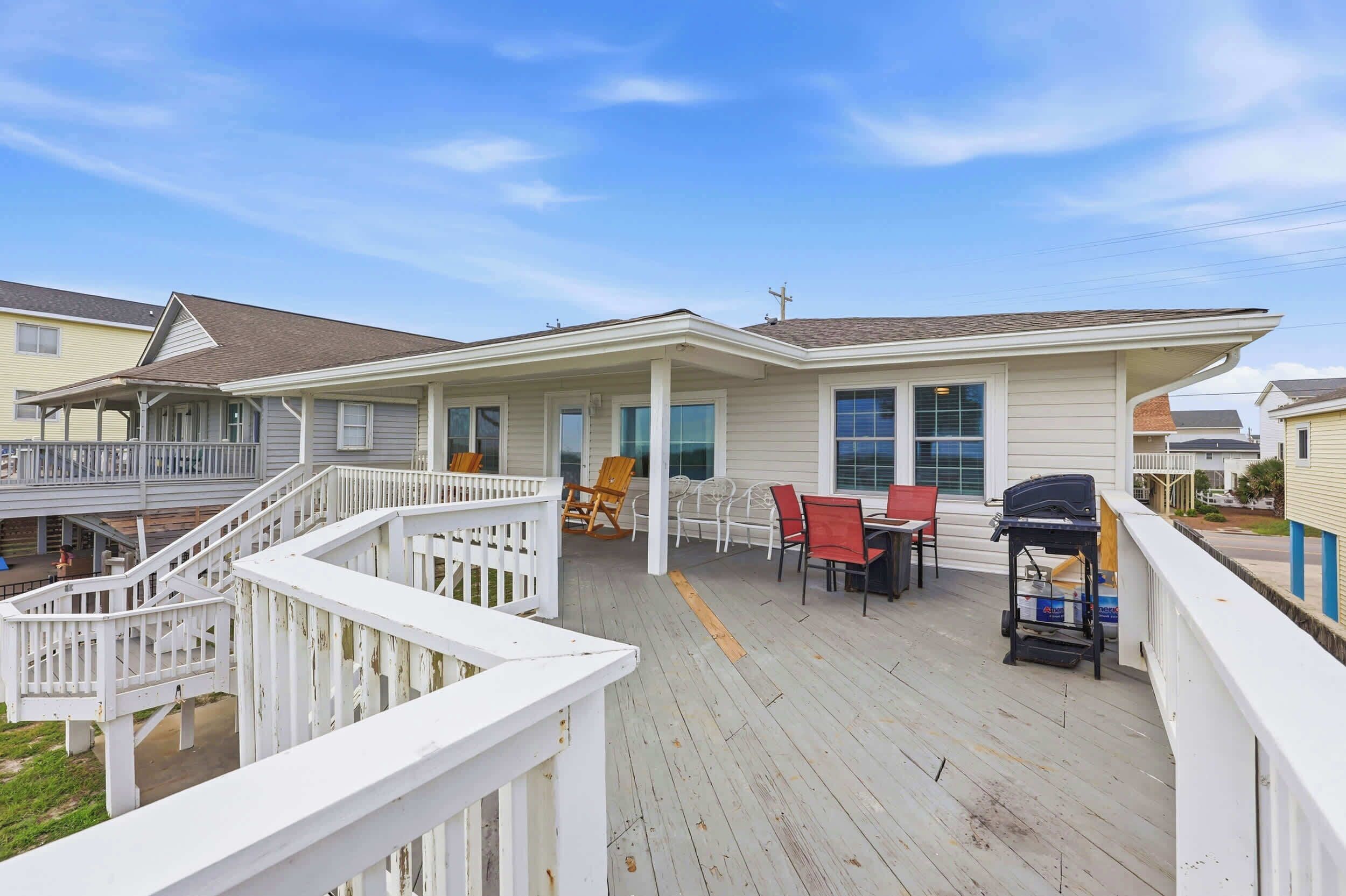 A residential deck with outdoor furniture, a barbecue grill, and a staircase leading to an upper level.