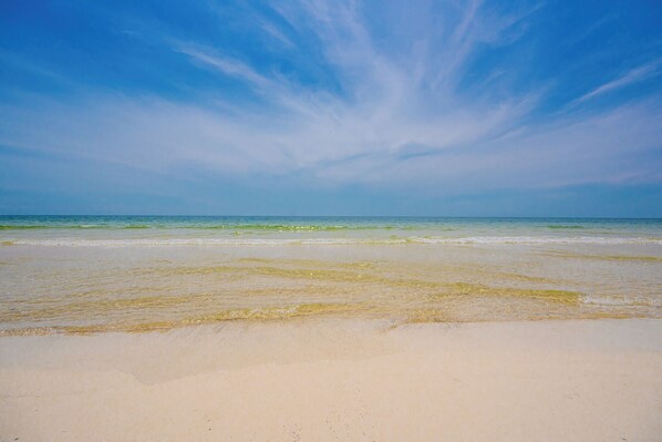 Une plage avec un ciel dégagé et une mer calme.