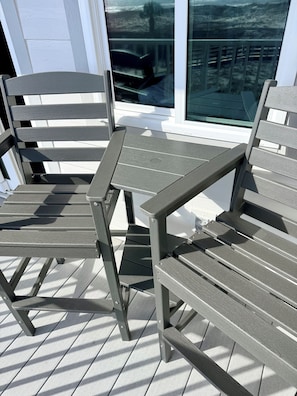 Eine Terrasse mit zwei grauen Metallstühlen und einem kleinen Tisch.