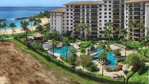 Un hotel con varios pisos, una zona de piscina con diferentes fuentes de agua y vistas a la playa.